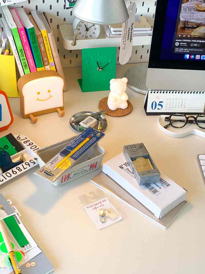 White-toned desk adorned with various stationery items and a green clock, creating a neat and simple home office space