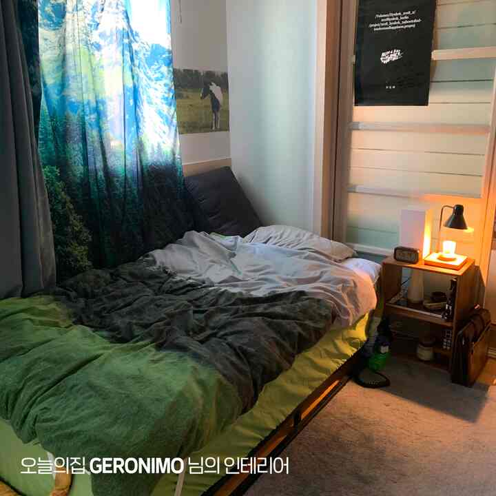 自然を思わせるグリーンの調和が美しい寝室、ベッドと遮光カーテン、暖かい照明のナイトスタンドが配置された雰囲気のあるインテリア