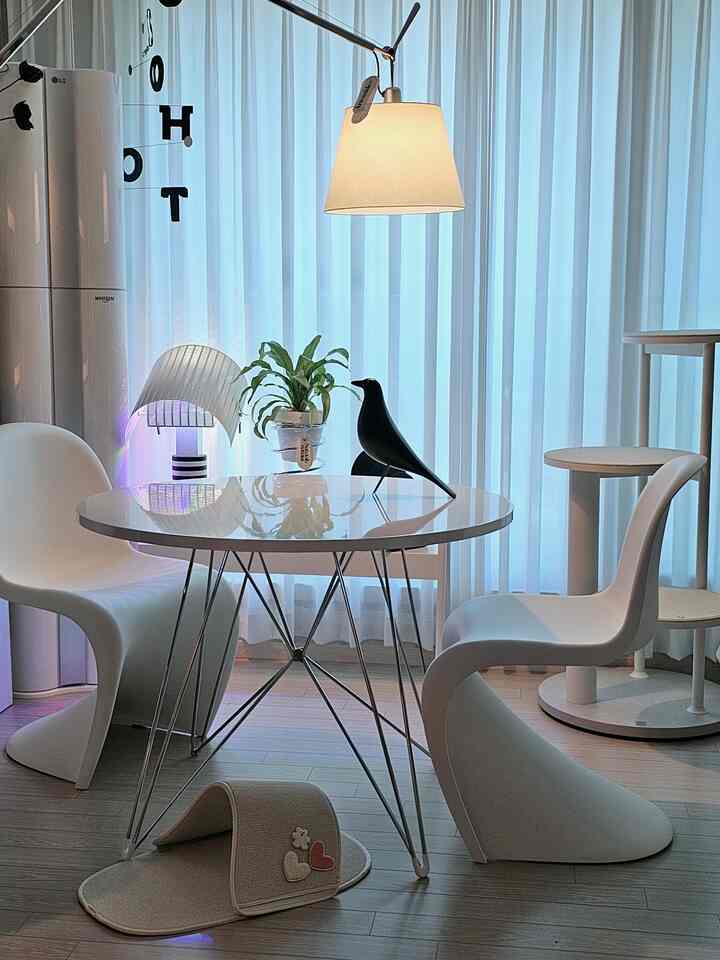 白とナチュラルトーンのリビング、円形テーブルと椅子、キャットタワーとかわいいペット用スリッパが配置されたシンプルな空間