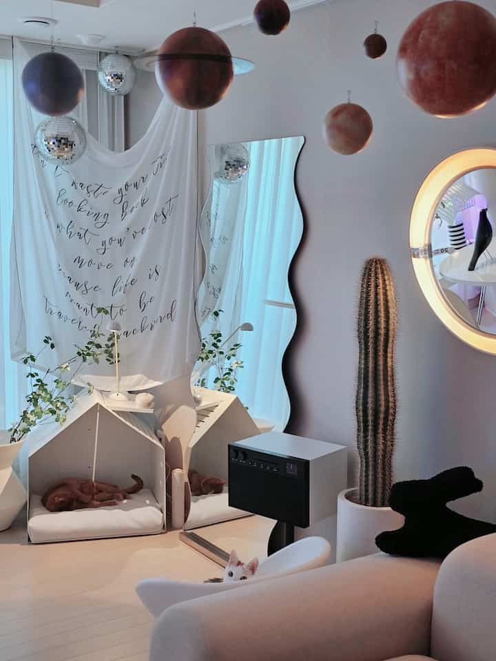 Natural-toned living room with white and beige hues featuring cat pet house and sofa creating a calm atmosphere