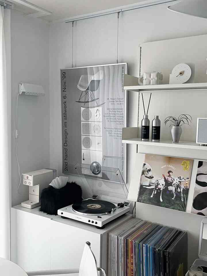 White-toned home office corner featuring a turntable, diffusers, and poster with a minimal and retro vibe