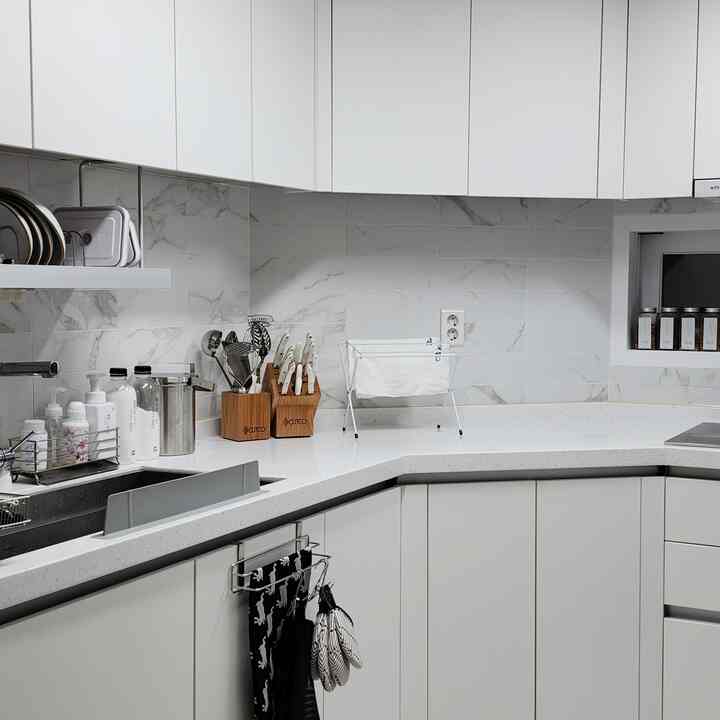 白とナチュラル調のキッチン、清潔感のある調理器具とタオルが配置された印象的な空間