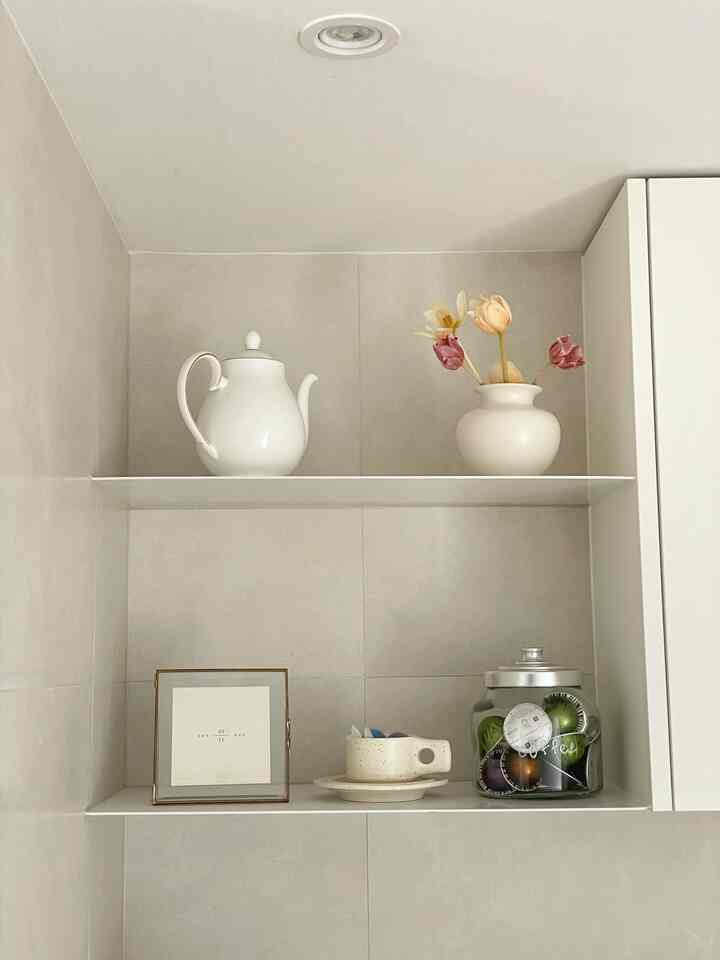 ホワイトトーンのキッチン棚にヴィンテージカラーのチューリップが入った花瓶と様々なオブジェが配置されたシンプルで落ち着いた雰囲気のインテリア