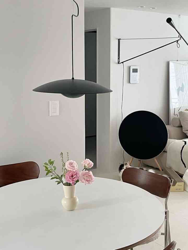 White and black toned living room featuring a round table with a vase and pendant light in a modern setting