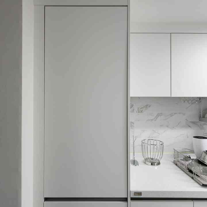 White-toned kitchen featuring a tall cabinet and metal storage baskets creating a clean kitchen space