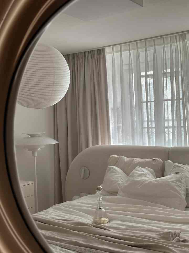 ベージュとホワイトの色調の寝室、柔らかい寝具と和紙ランプが配置されたナチュラルでシンプルな雰囲気のインテリア