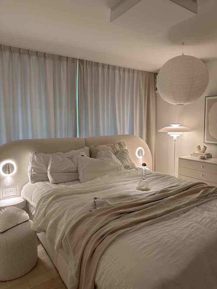 Beige and ivory toned bedroom featuring a round paper lamp and sleek bed, creating a cozy hotel-like atmosphere