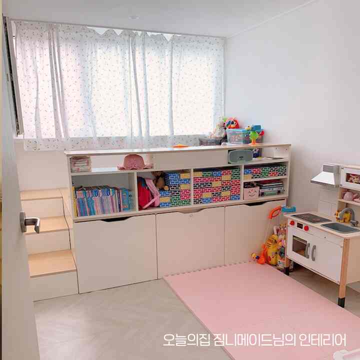 明るい白とナチュラルカラーの子供部屋、整理された収納とおままごとキッチンセットが配置された雰囲気のあるインテリア