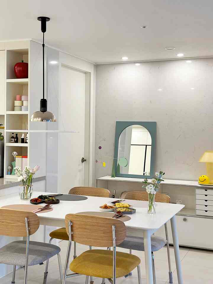 Bright white and wood-toned dining room featuring a simple dining table and chairs with table settings for a birthday celebration