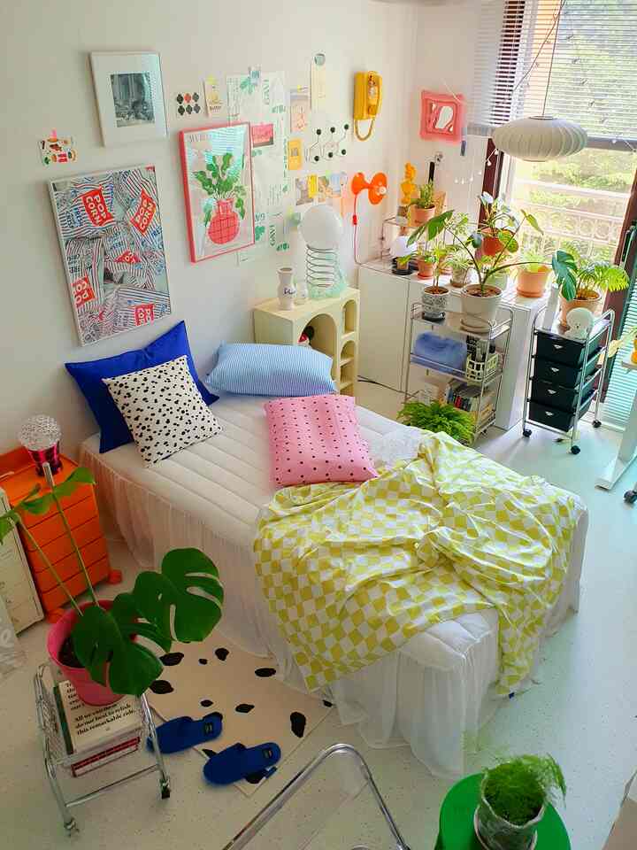 A white and yellow toned bedroom featuring a single bed with patterned pillows in a compact and cozy setting