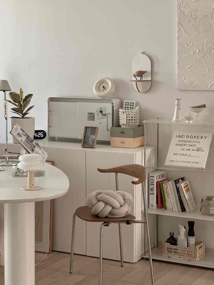 White and natural toned home office featuring a desk, storage cabinets, and acrylic shelves arranged in a neat workspace interior