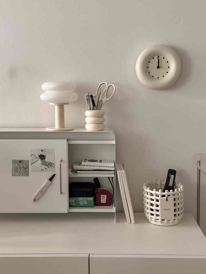 White and natural-toned desk space featuring a slim storage cabinet and ceramic basket arranged with a clean, simple aesthetic