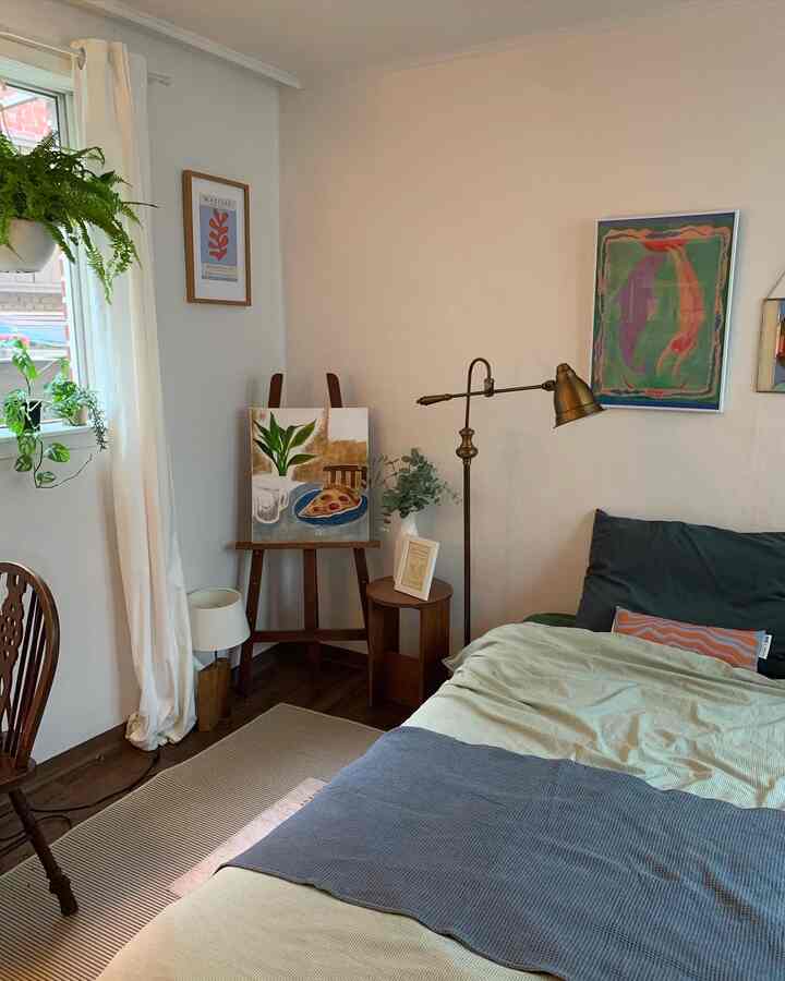 Beige walls and curtains in a bedroom with navy and beige bedding, wood-tone furniture, and plants creating a natural atmosphere