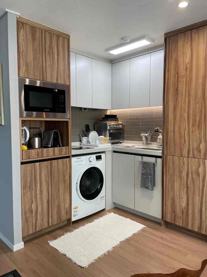 Natural tone small kitchen featuring wood cabinets and white upper cupboards with a clean organized look