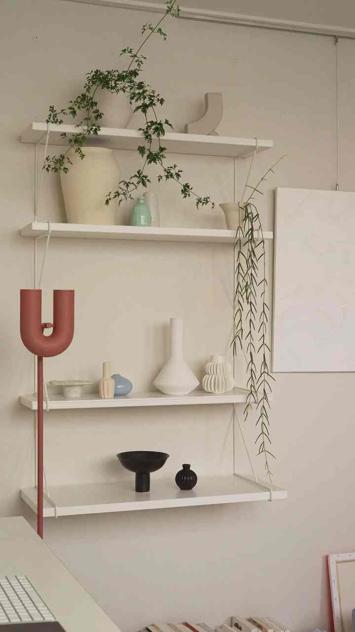 ナチュラルな色調の壁に白い棚が設置され、花瓶と植物が配置されたシンプルなインテリア空間