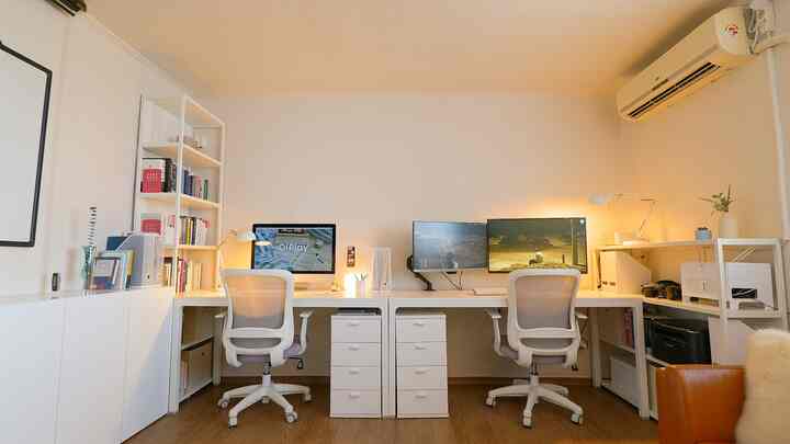 A bright and clean white and wood tone home office workspace featuring two desks and office chairs