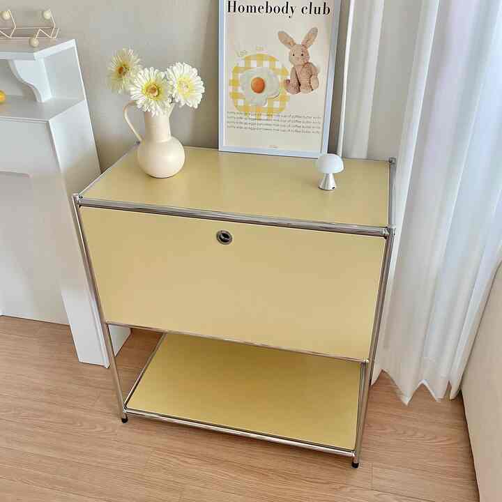 バター色の収納キャビネットと白いカーテンが調和するモダンなリビング空間