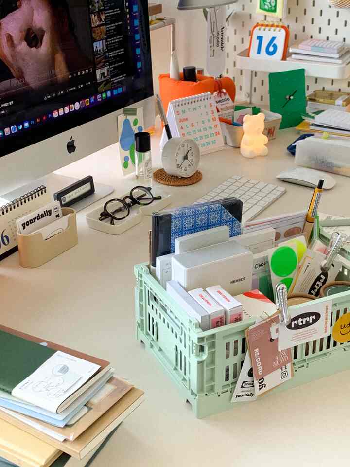 Simple home office space featuring a mint foldable basket and a tidy desk with organized stationery