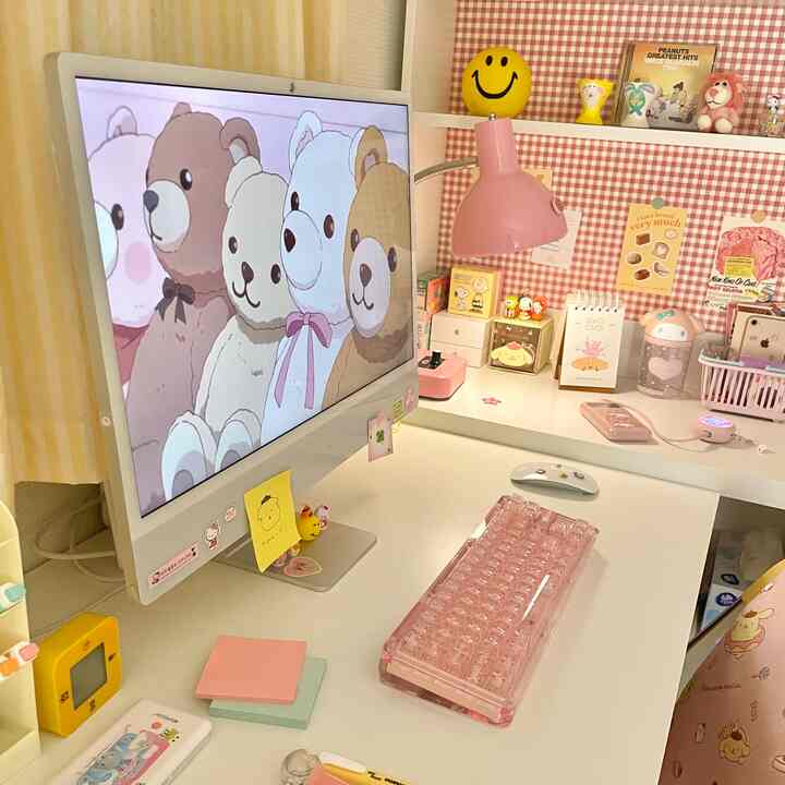 Compact home office in pink and white tones featuring a transparent pink keyboard and desk lamp creating a cozy workspace