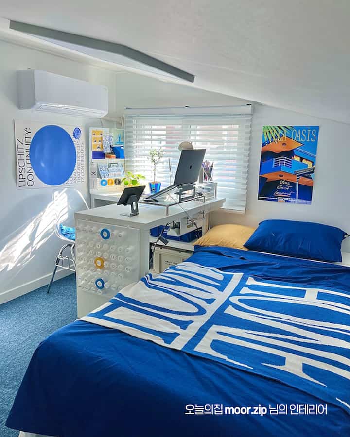 白い壁とブルーの寝具が印象的な6畳の個室寝室、デスクとパソコンがあるモダンなホームオフィス空間
