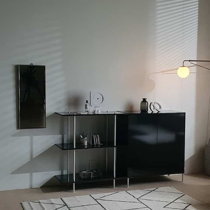 Warm-toned studio living room with black steel cabinet, full-length mirror, and cozy lighting in mid-century modern style