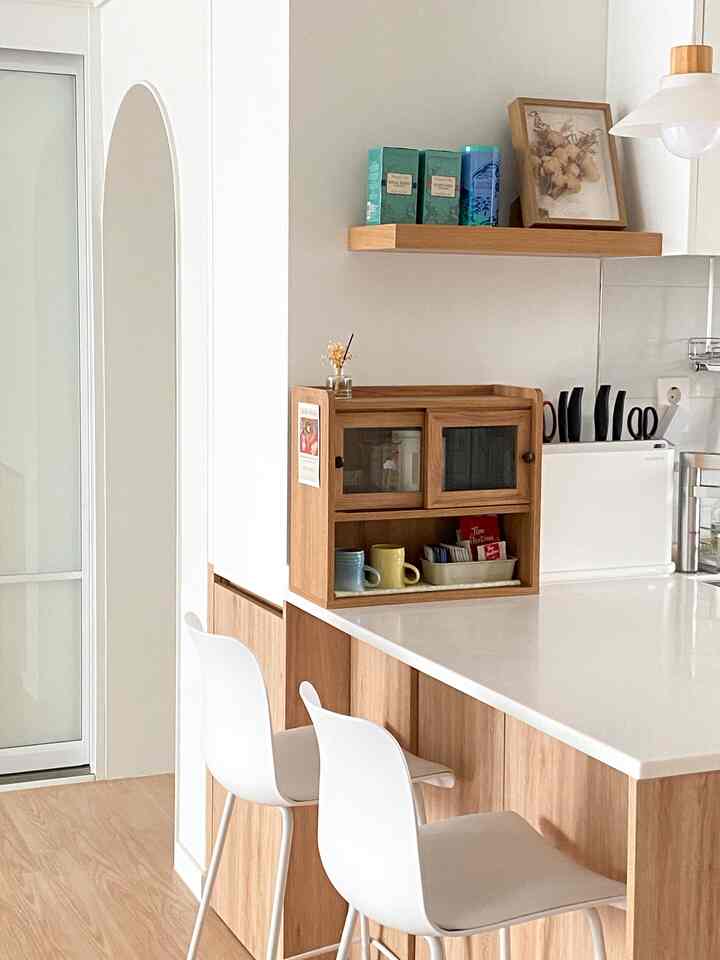 木目調と白を基調としたキッチン、キッチンアイランドと収納棚が配置された印象的な空間