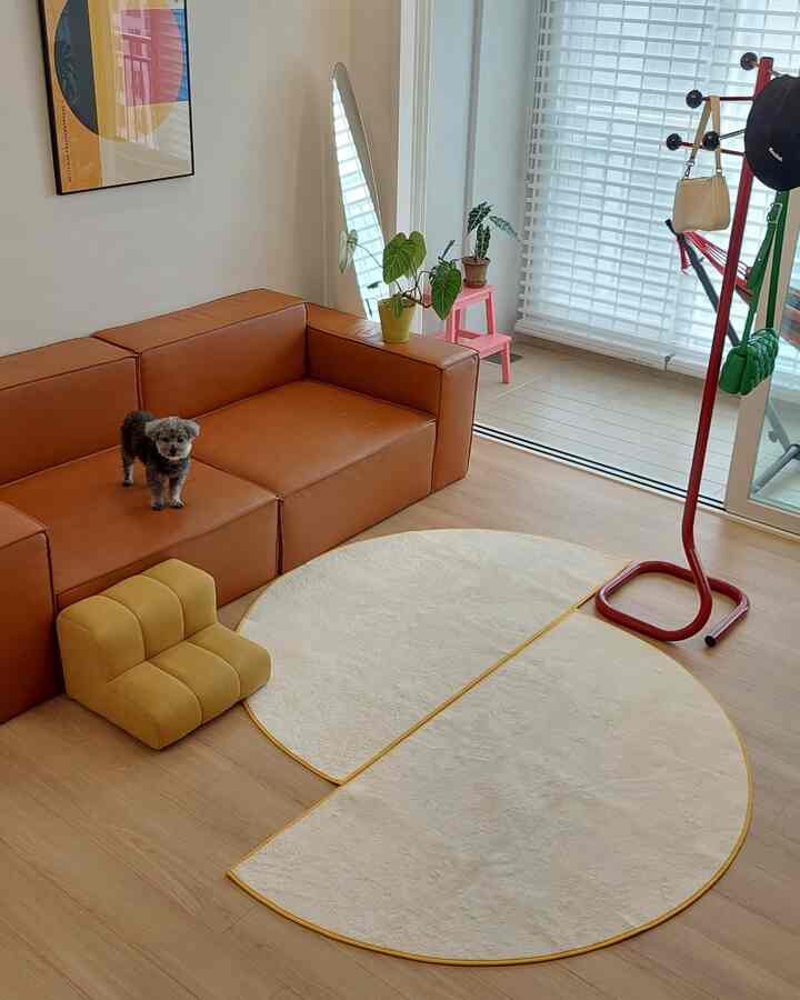 Natural modern living room featuring brown leather sofa with small dog and yellow pet steps, creating a cozy atmosphere