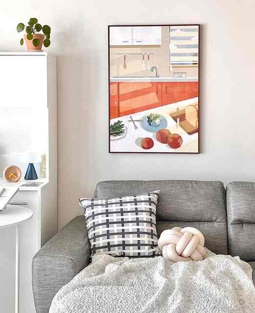 グレーのソファと白い壁、印象的なポスター額縁が配置されたモダンでナチュラルなリビング空間