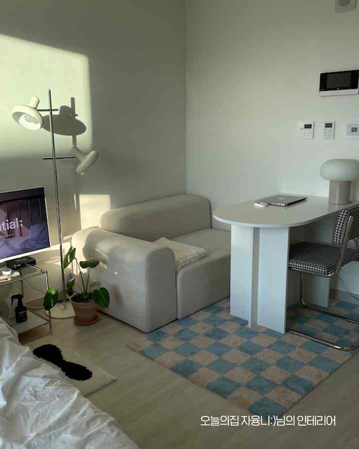 White and blue toned studio living room featuring a simple sofa and dining table with a modern atmosphere