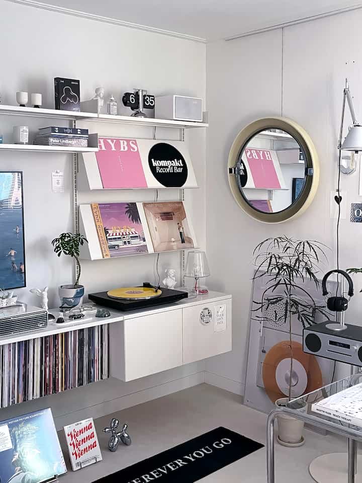 Modern white-toned living room featuring a round mirror and music-related elements in a clean interior space