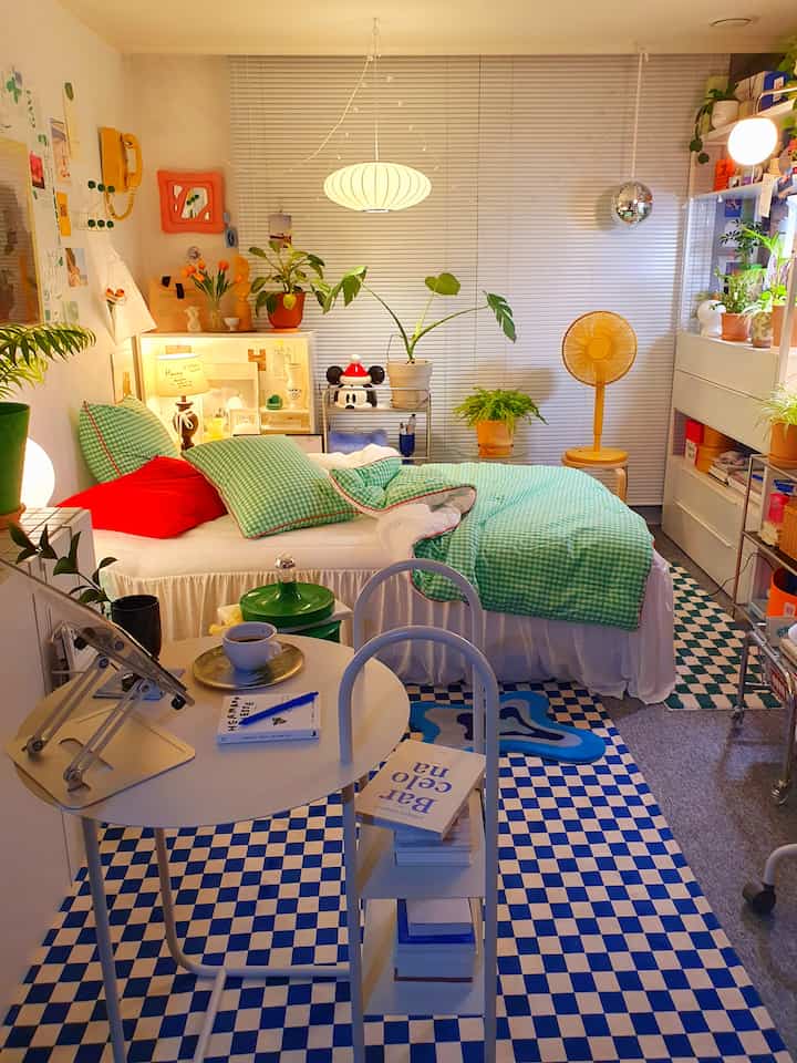 White and green toned bedroom featuring a pendant light and checkered rug in a cozy compact space