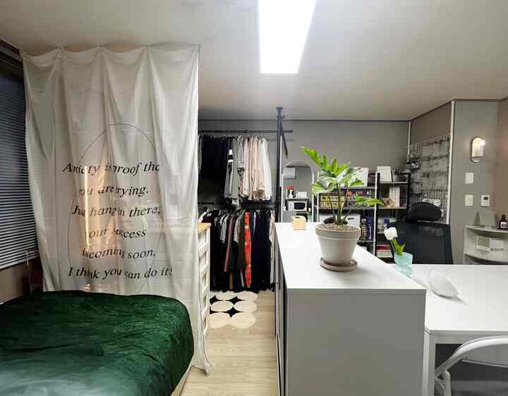 ベージュ調のコンパクトな寝室、ベッドとデスク、多数の収納家具が配置された居心地の良い実用的なインテリア