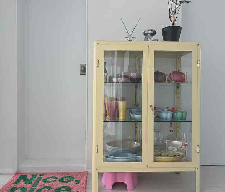 ナチュラルな色調のキッチン空間、クリーム色のガラス扉キャビネットにル・クルーゼのコレクションが整然と並べられた雰囲気あるインテリア