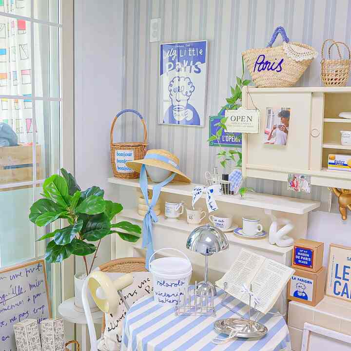 青と白のトーンのカフェ風インテリア、かわいい小物と植物が配置された雰囲気のある空間