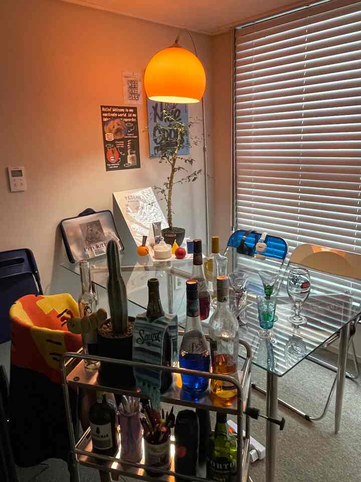 オレンジ色の照明が灯るミッドセンチュリーモダンのホームバー、ガラスのテーブルとバーカートが配置された雰囲気のある空間