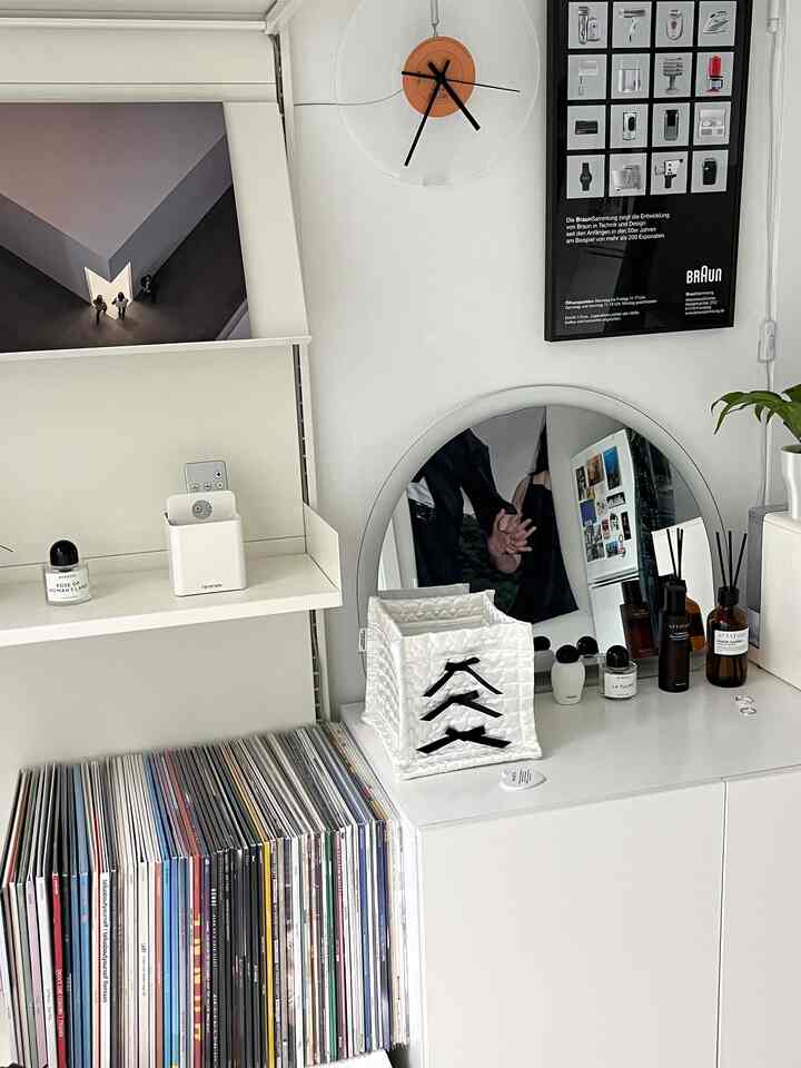 White-toned music listening space featuring LP storage, a semicircular mirror, and decorative items in a clean interior