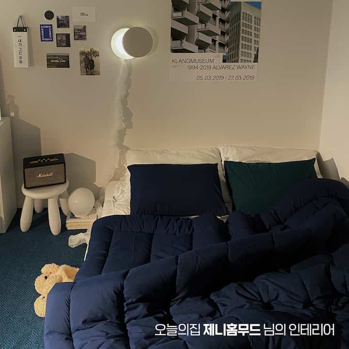 ネイビーとホワイトの色調の寝室、中央にソファベッドと壁にポスターが配置された落ち着いた雰囲気のインテリア