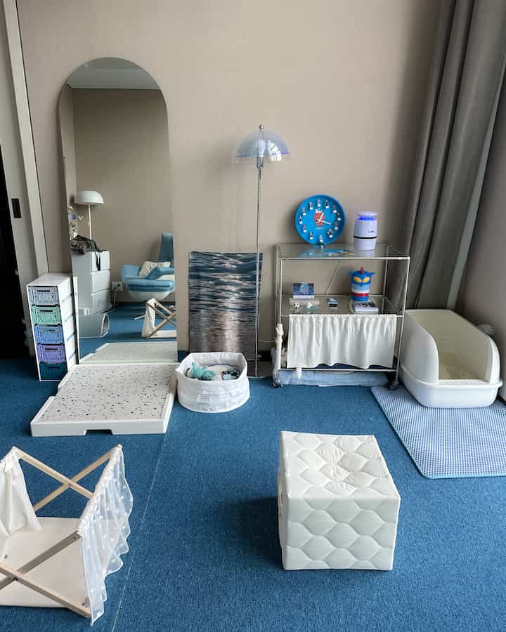 青いカーペットと白い小物が調和したリビング、猫の隠れ家と爪とぎが配置された居心地の良いペットスペース