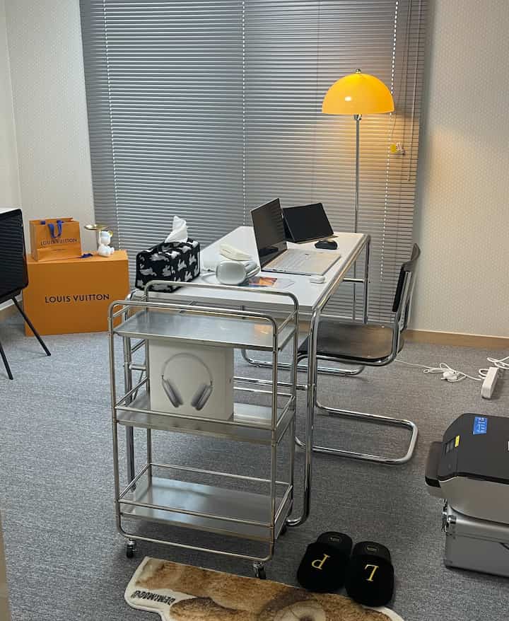 白とグレーのトーンのミッドセンチュリーモダンな書斎、白い机とクロームの棚、黄色いフロアランプが配置された印象的な空間