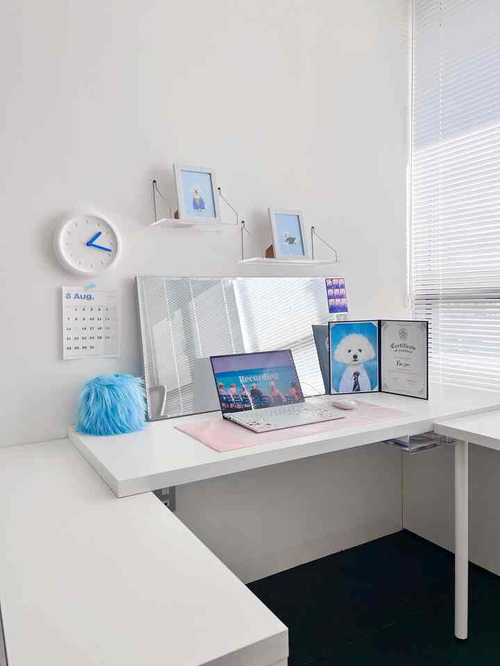 White and blue toned home office space featuring a clean desk with small decor, highlighting a pet dog photo in a bright workspace