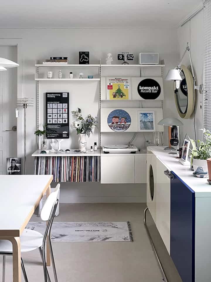 Bright white-toned living room featuring Mid-Century Modern Artek furniture, a turntable with LP records, and posters arranged stylishly