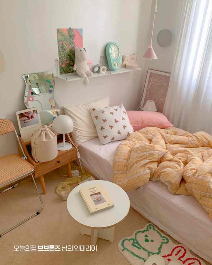 薄いベージュとイエローの色調の印象的な寝室、ベッドとナイトテーブル、ラグが配置されたシンプルでナチュラルなインテリア