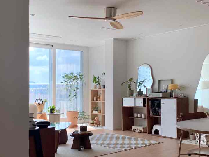 Bright living room featuring white walls and wood tone furniture, filled with natural light and plants for a natural modern vibe