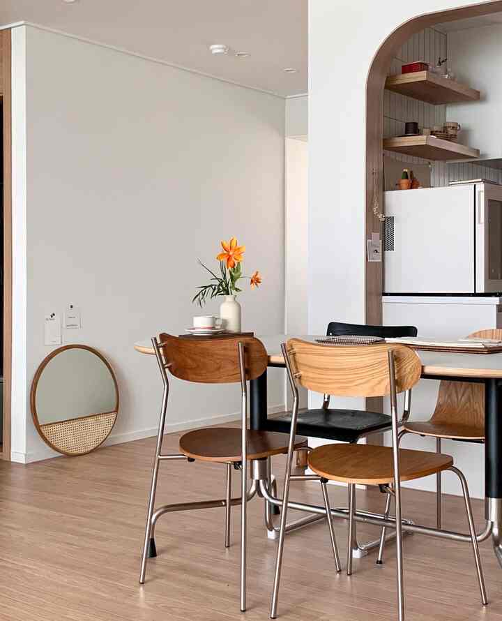 ホワイトの壁と木目調家具が調和するコンパクトなダイニングルーム、中央に配置されたダイニングテーブルと椅子が印象的なシンプルな新婚の家のキッチン