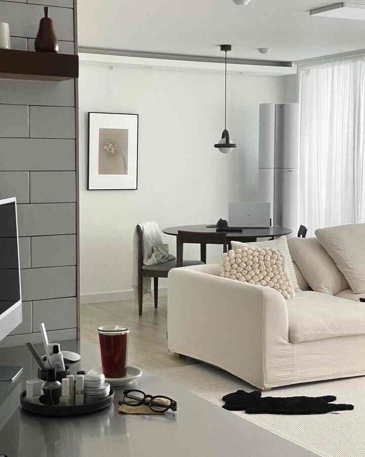 ホワイトとナチュラルトーンのリビング、クリーム色のソファとラウンドテーブル、ペンダントライトが調和するモダンな空間