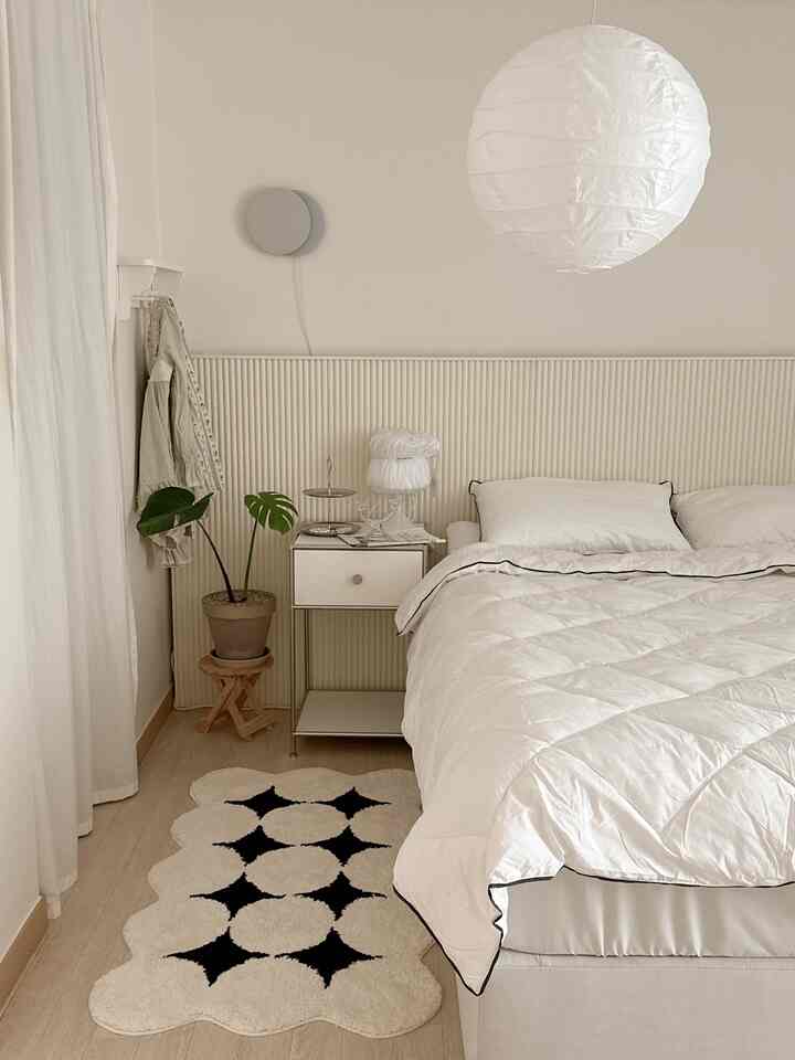 ホワイトとベージュの寝室、テンバボードのベッドとナイトテーブル、植物が配置されたシンプルでナチュラルなインテリア