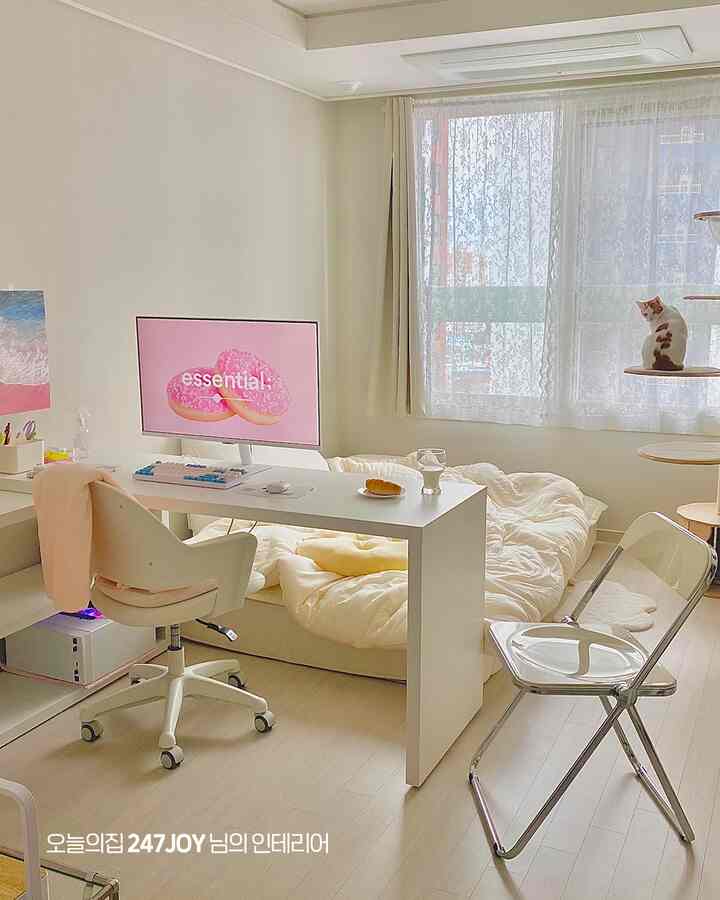 白とアイボリーのトーンのコンパクトなワンルーム、デスクと布団が配置され、猫と暮らす居心地の良いホームオフィス