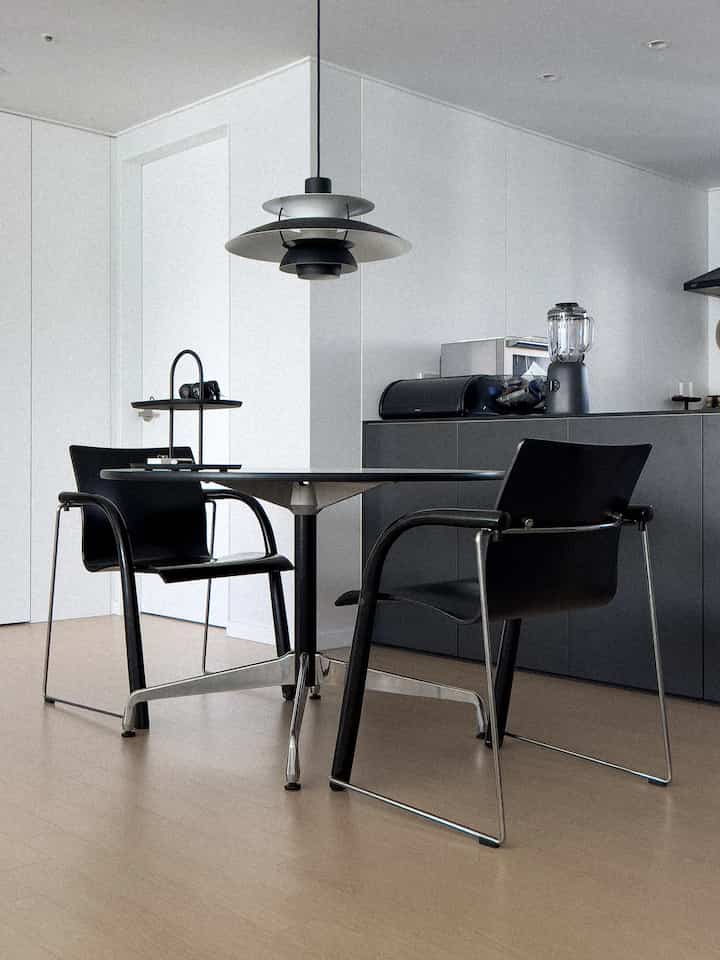 Modern dining room in black and wood tones featuring two dining chairs and a pendant light, creating a cozy atmosphere