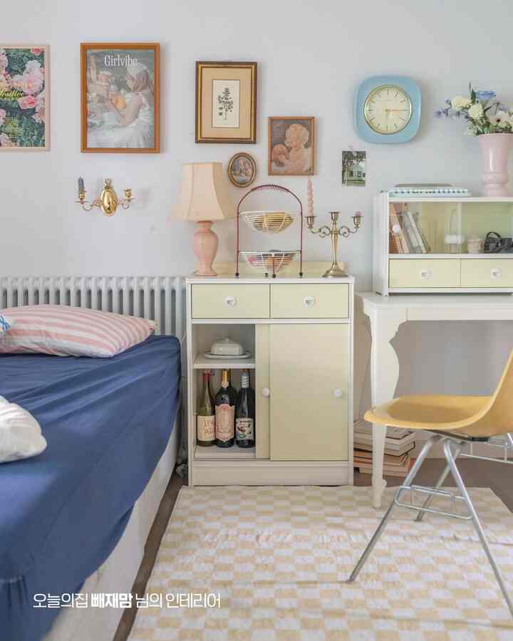 ホワイトとブルーの色調が特徴の寝室、ベッドとナイトテーブル、デスクが配置されたレトロで雰囲気のあるインテリア