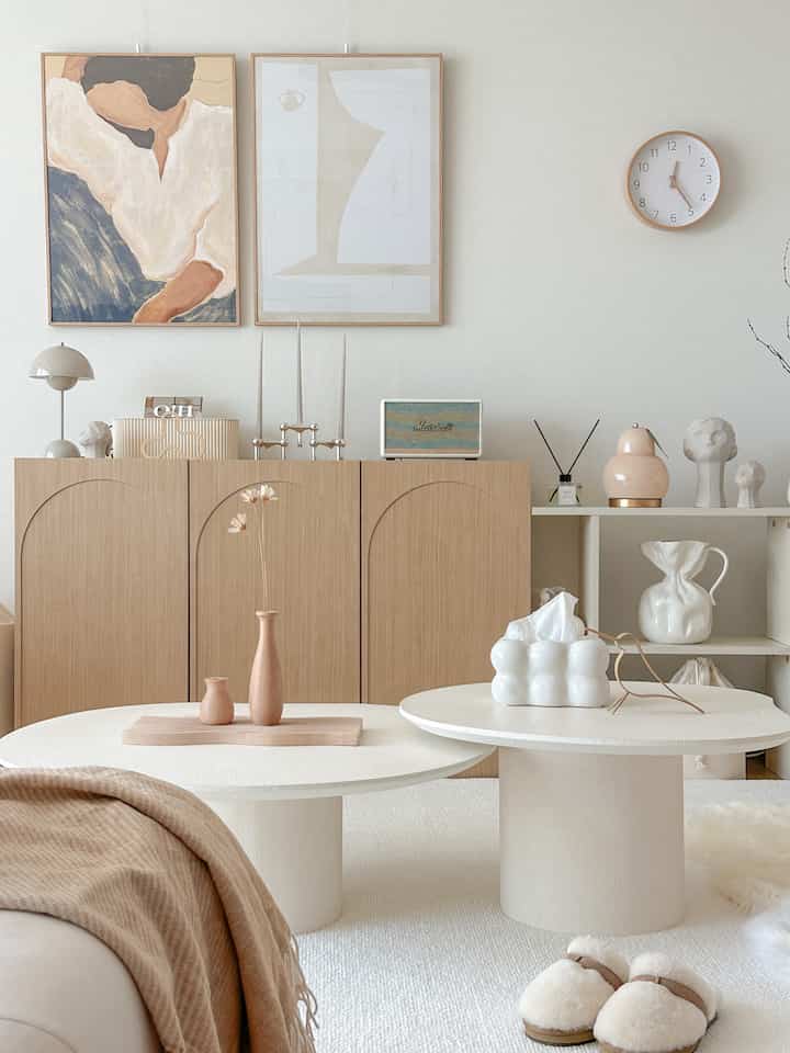 Natural wood tones and creamy whites define the living room with a wool rug and blanket creating a warm, cozy atmosphere